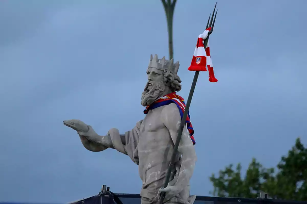 Statue of Neptune with scarf and Atlético de Madrid flag on his trident.