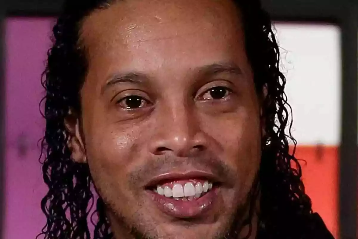 Ronaldinho sonriendo con cabello rizado y largo.