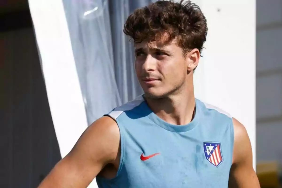 Un hombre con camiseta sin mangas del Atlético de Madrid mirando hacia la derecha.