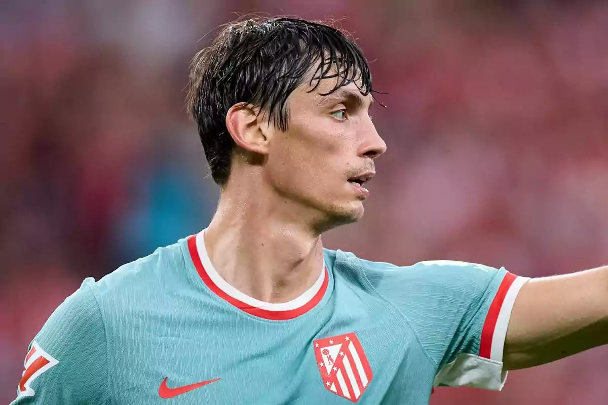 Jugador de fútbol con camiseta del Atlético de Madrid en el campo de juego.