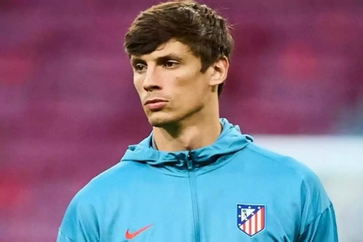 Un jugador de fútbol con una chaqueta azul del Atlético de Madrid en un estadio.