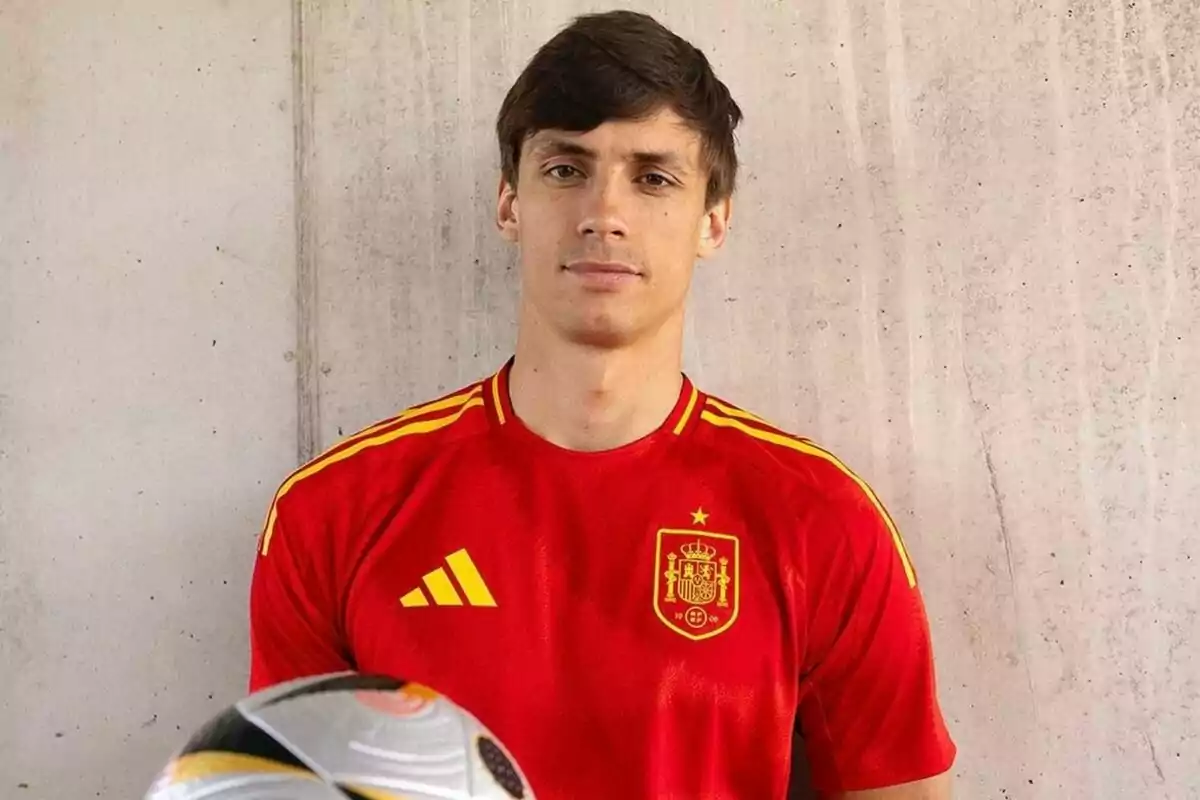 Un jugador de fútbol con la camiseta de la selección española sosteniendo un balón.