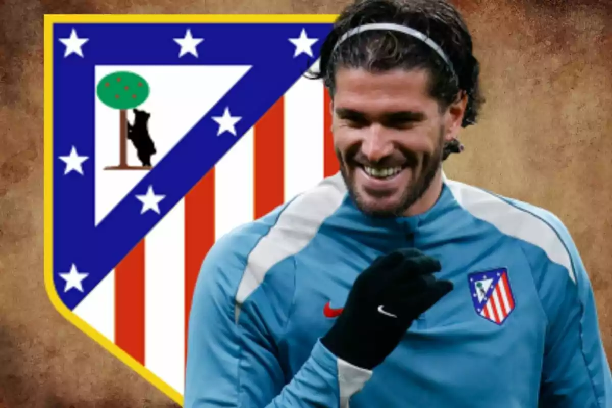 Un jugador de fútbol sonriente con el escudo del Atlético de Madrid de fondo.