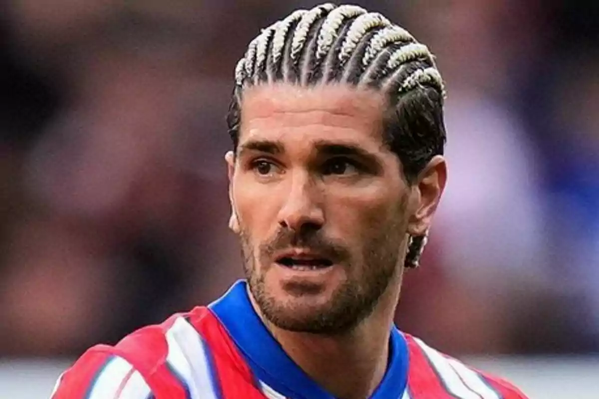 Un hombre con trenzas rubias y barba, vistiendo una camiseta de rayas rojas y blancas.