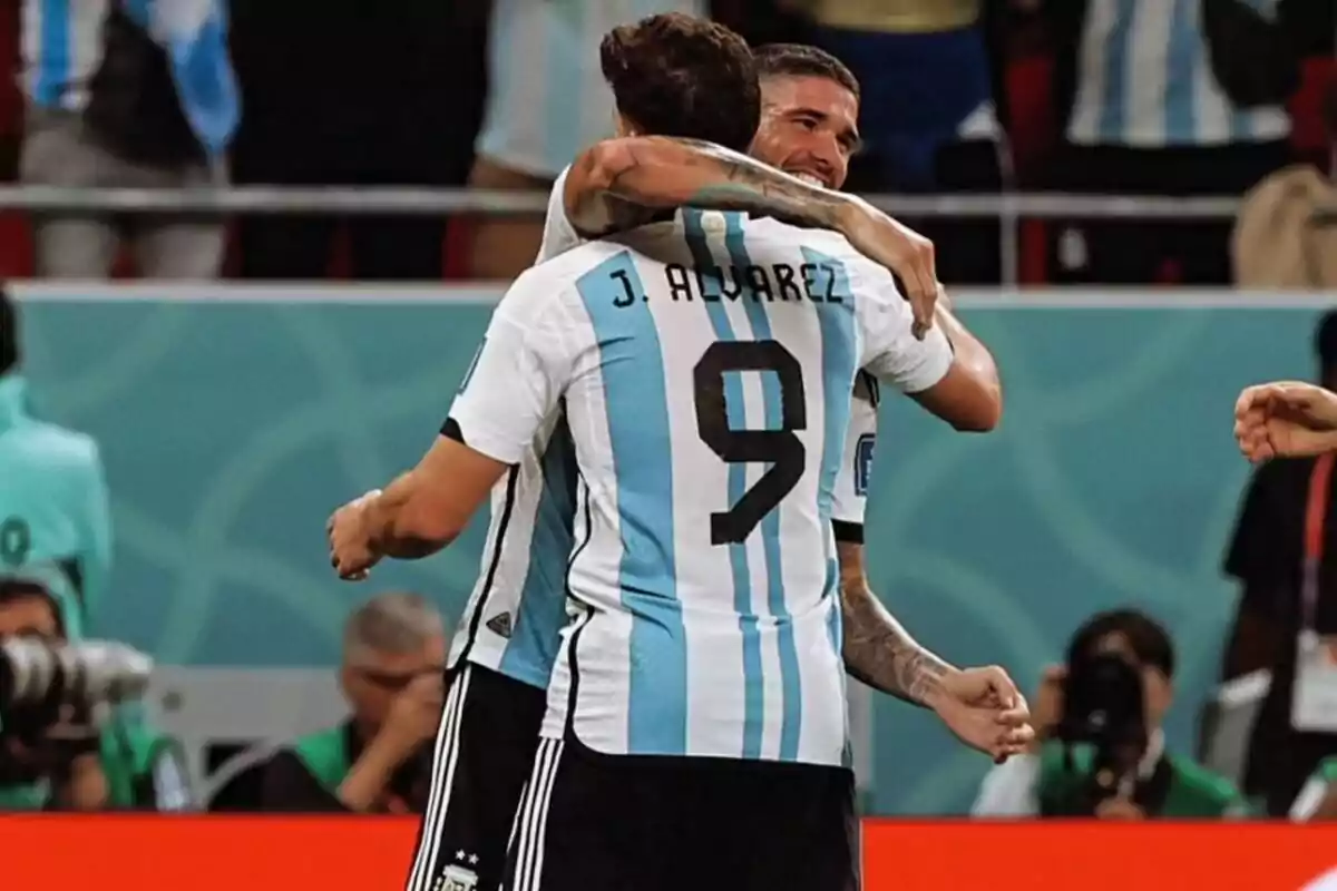 Dos jugadores de la selección argentina de fútbol se abrazan celebrando un gol en un estadio.