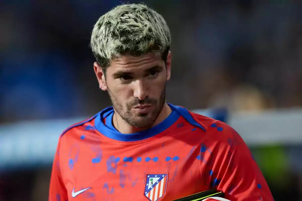 Un jugador de fútbol con camiseta roja y azul del Atlético de Madrid en el campo.