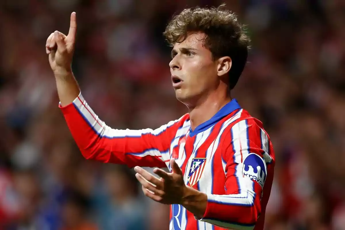 Jugador de fútbol con uniforme rojo y blanco gesticulando en el campo.