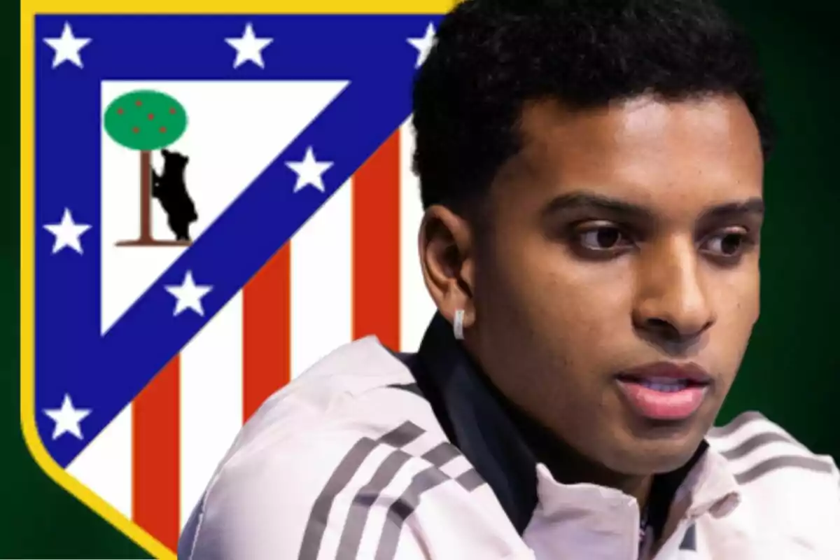 Un hombre con una chaqueta clara está frente al escudo del Atlético de Madrid.