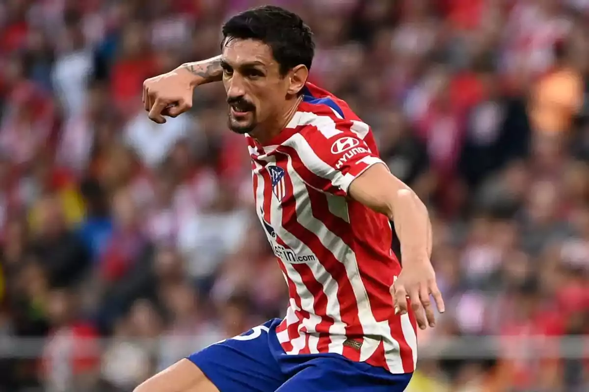 Jugador de fútbol con camiseta del Atlético de Madrid en acción durante un partido.