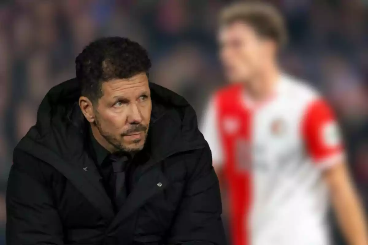 Un hombre con chaqueta negra observa hacia la izquierda mientras una persona con uniforme deportivo rojo y blanco aparece desenfocada en el fondo.