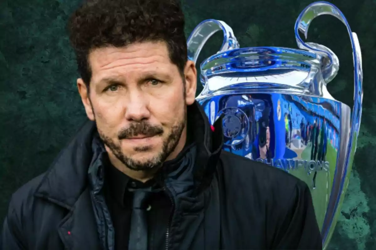 Un hombre con barba y cabello rizado frente a un trofeo grande y plateado.