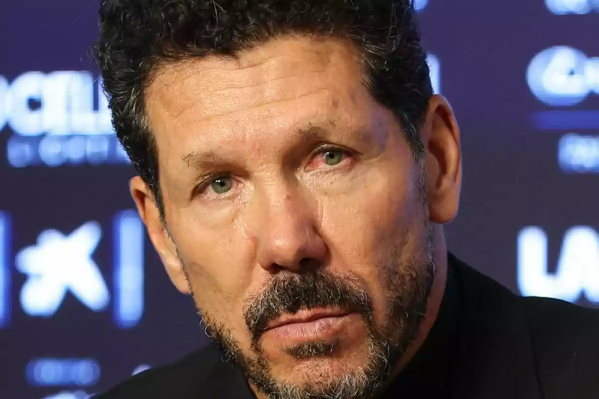 Un hombre con barba y cabello rizado en una conferencia de prensa.