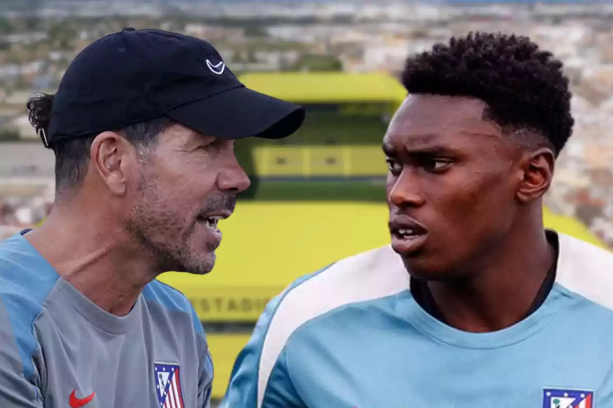 Un entrenador de fútbol hablando con un jugador en un estadio.