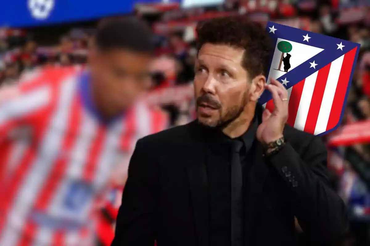 Un hombre con traje negro y barba, con el logo del Atlético de Madrid en el fondo, en un estadio de fútbol.