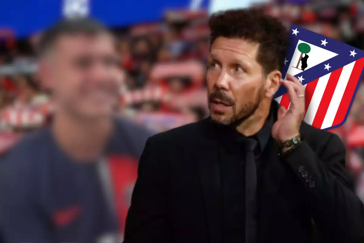 Un hombre con traje negro y barba, con el escudo del Atlético de Madrid en el fondo.