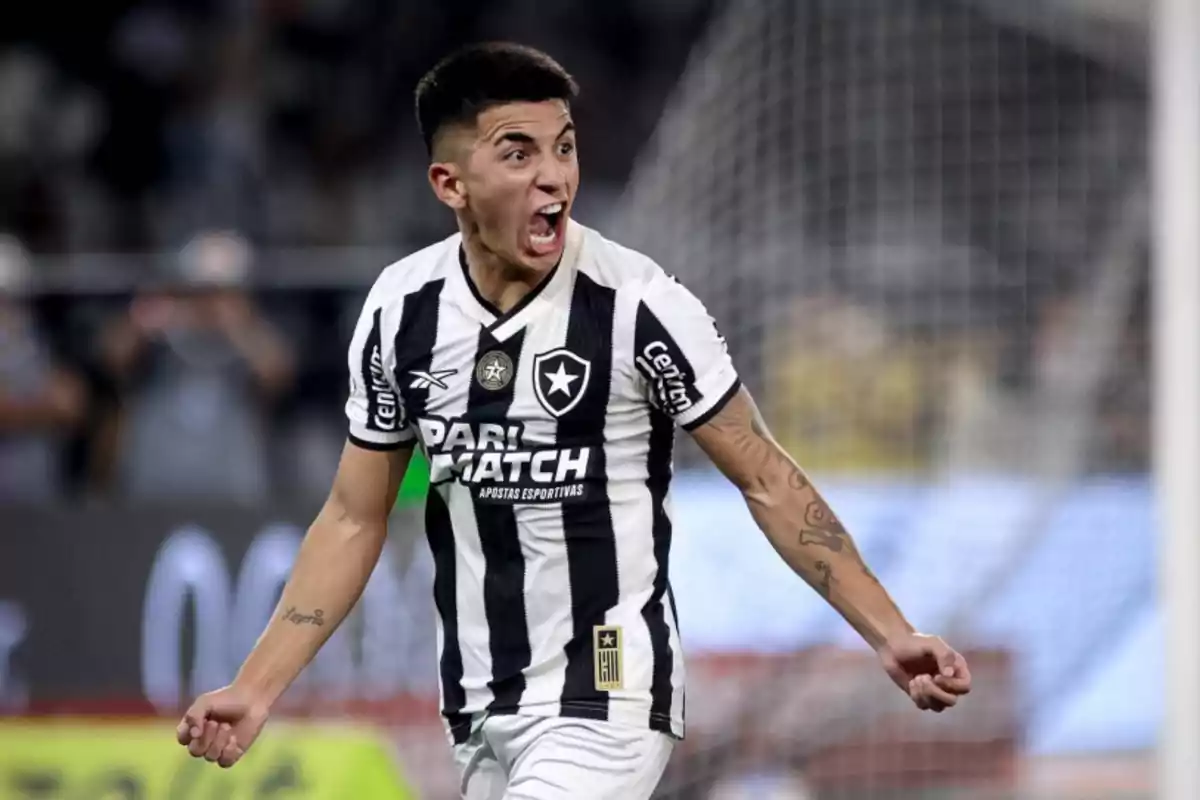 Jugador de fútbol celebrando con emoción en el campo mientras viste el uniforme de su equipo.