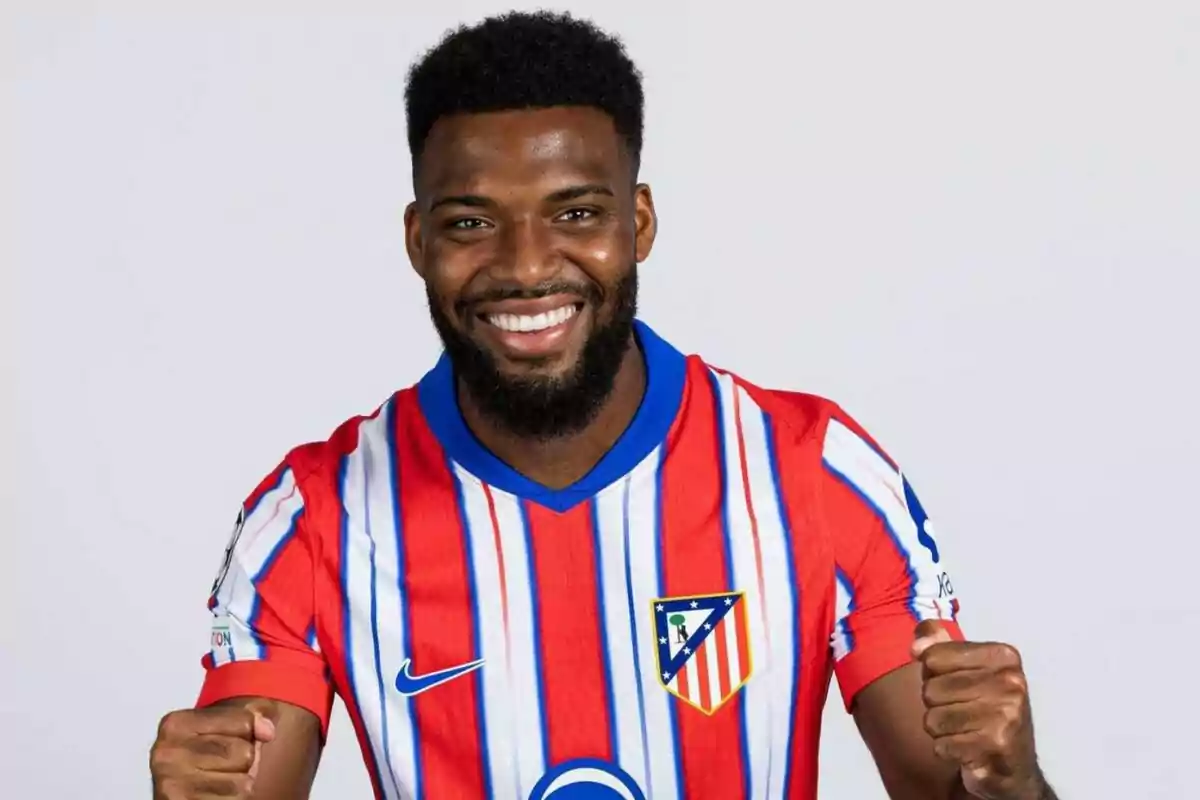 A smiling football player wearing an Atlético de Madrid shirt.