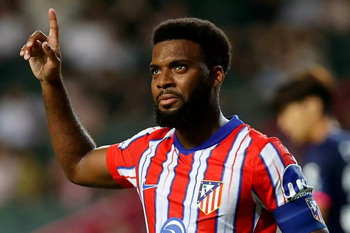 Jugador de fútbol con uniforme del Atlético de Madrid levantando un dedo.