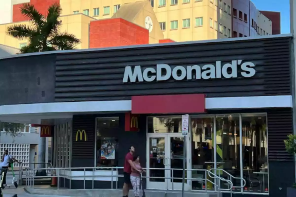 Frente de un restaurante McDonald's con personas en patinetas eléctricas y un edificio de fondo. Frente de un restaurante McDonald's con personas en patinetas eléctricas y un edificio de fondo.