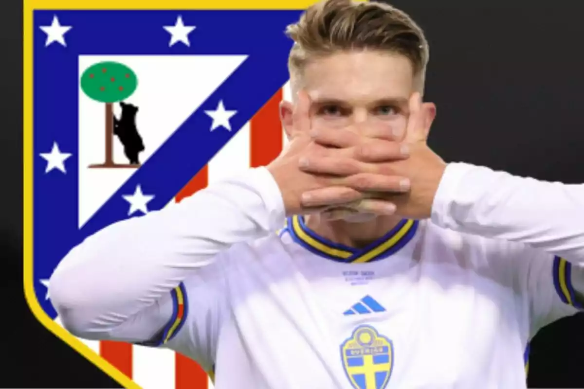 A player in a white uniform with blue and yellow details covers his mouth with his hands, with the Atlético de Madrid crest in the background.