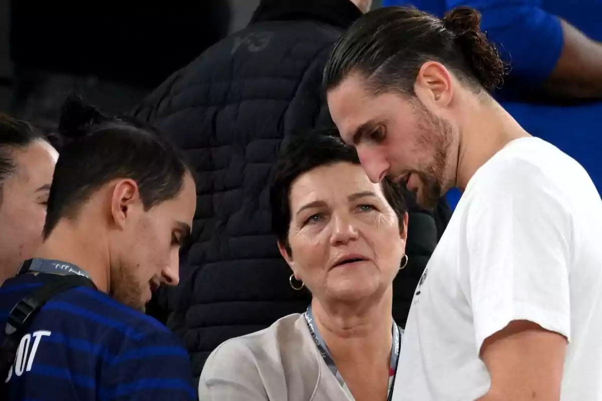 Three people talking at a sporting event.