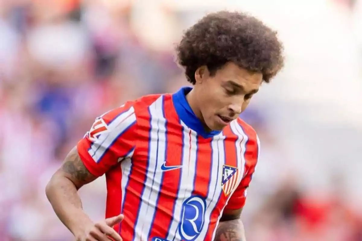 Jugador de fútbol con camiseta a rayas rojas y blancas en el campo.