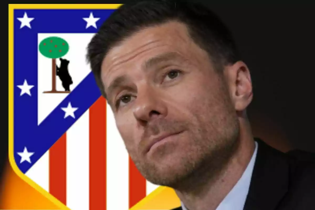 Hombre de cabello corto y barba recortada con el escudo del Atlético de Madrid de fondo