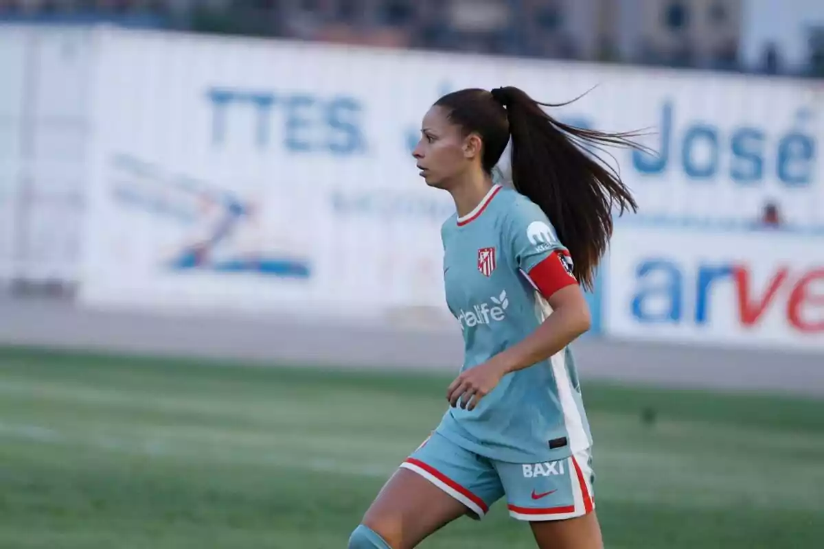 Una jugadora de fútbol con uniforme celeste y rojo corre en el campo durante un partido.