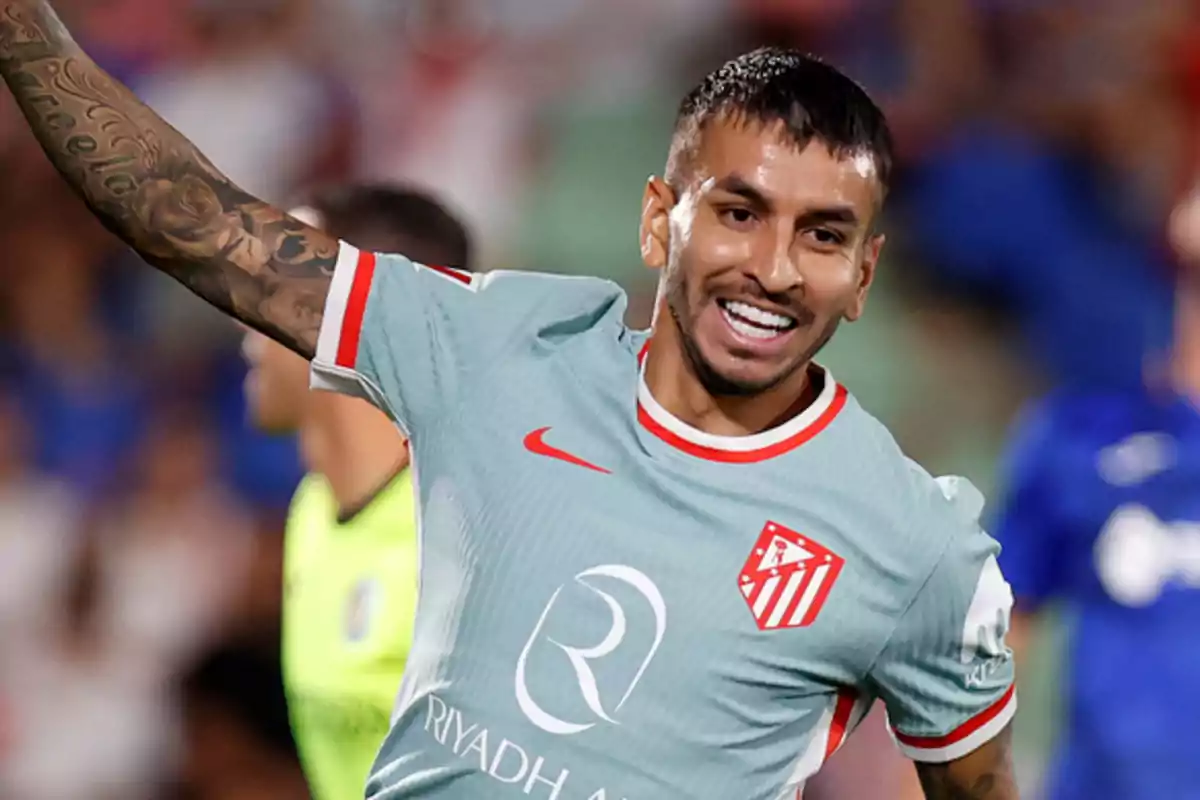 Un jugador de fútbol con uniforme gris y detalles rojos celebra en el campo.